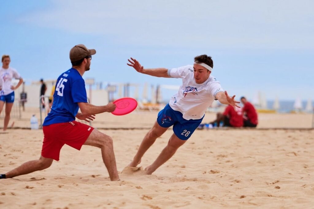 Beach Ultimate Frisbee tournament featuring teamwork, fast-paced action, and spectators relaxing near the seaside.