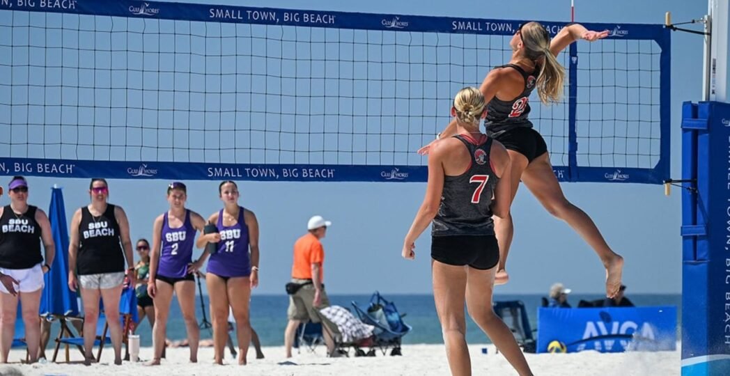 Beach volleyball tournament beside the ocean with athletes competing on sandy courts during a sunny coastal sports event.