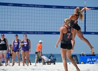 Beach volleyball tournament beside the ocean with athletes competing on sandy courts during a sunny coastal sports event.